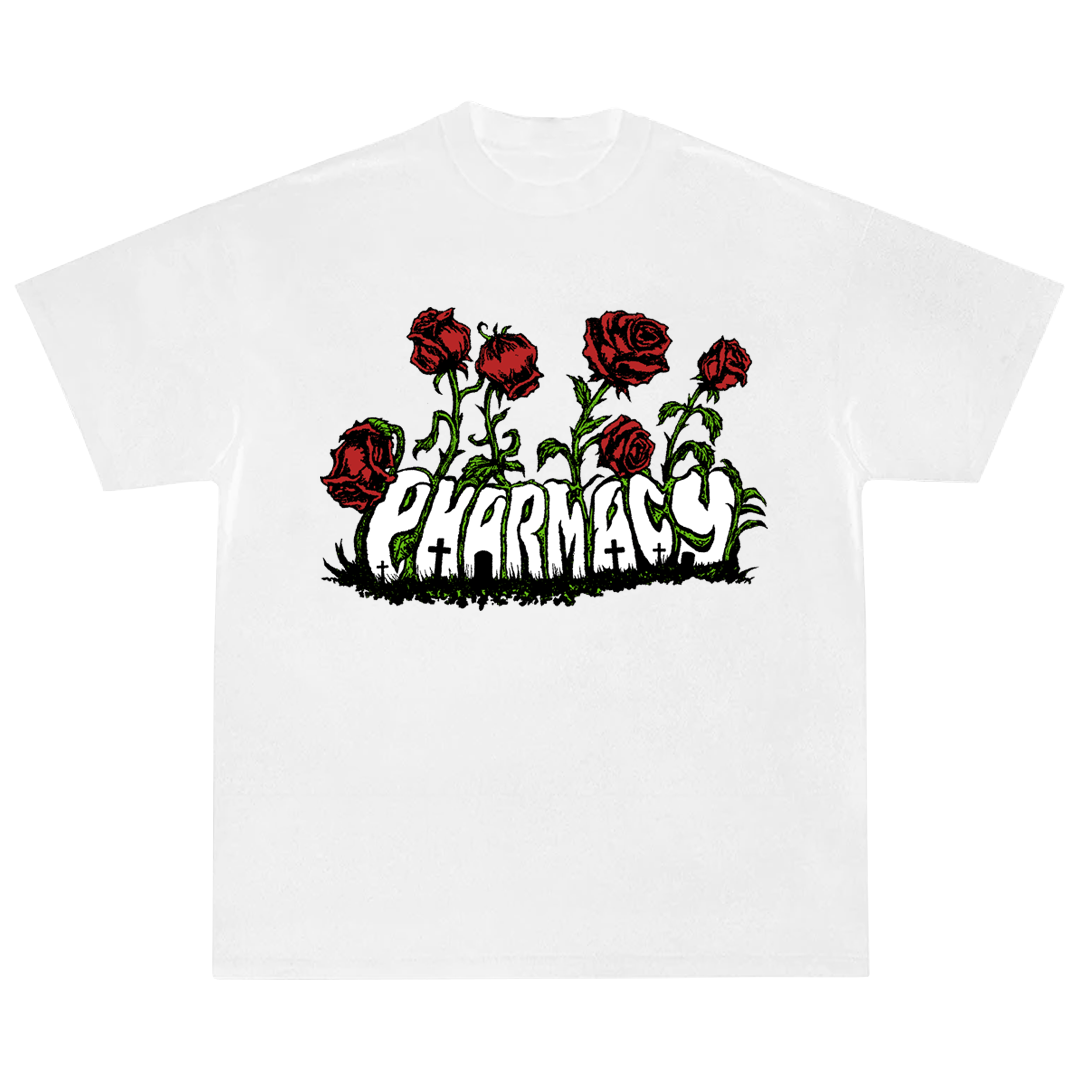 A white short-sleeve crewneck t-shirt featuring a graphic print of red roses with green stems and thorns rising above the word 'PHARMACY' in a stylized white font with black outlines.