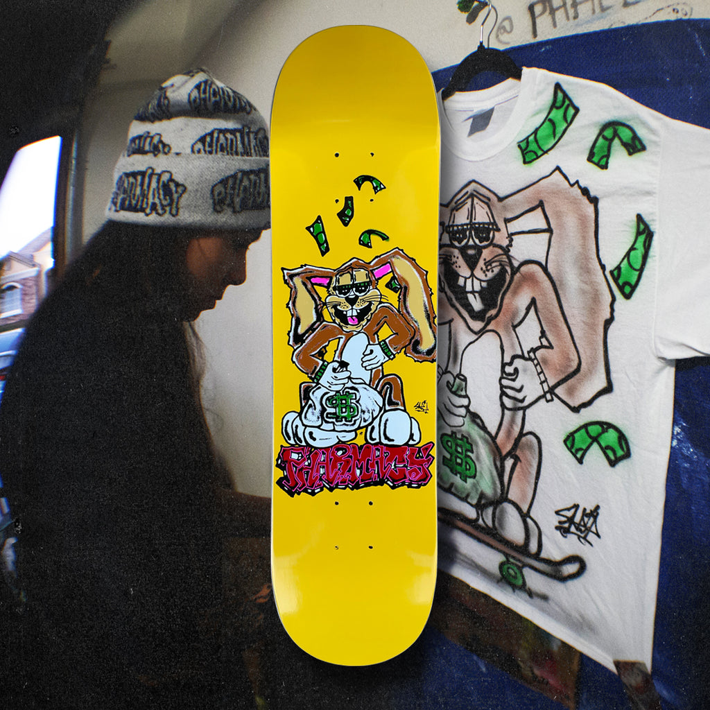 Yellow skateboard deck with cartoon bunny character. Image of the artist air-brush painting the artwork.
